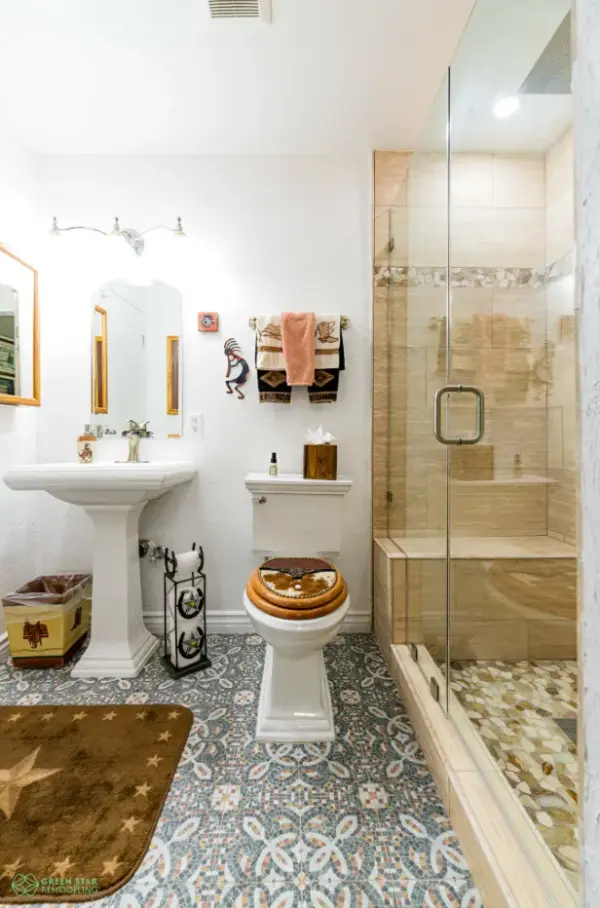 A southwestern-themed bathroom remodel by Green Star Remodeling in Calabasas featuring patterned floor tile, a pedestal sink, and a walk-in glass shower with a built-in bench and pebble tile floor.