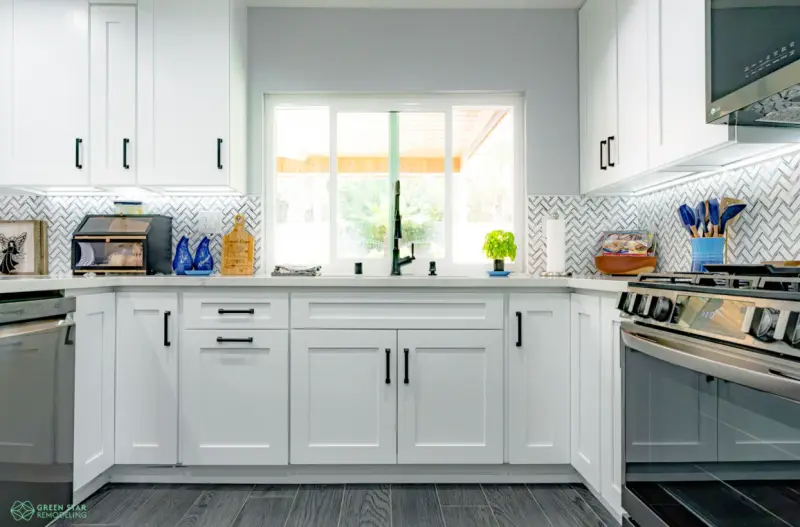 Modern kitchen remodel in Santa Clarita featuring white shaker cabinets, dark wood-look flooring, stainless steel dishwasher, and white quartz countertops by Green Star Remodeling.