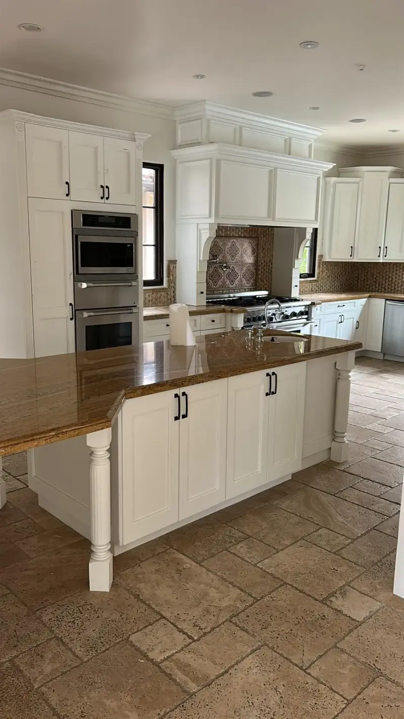 Modern white kitchen with a granite island and travertine flooring in Calabasas.