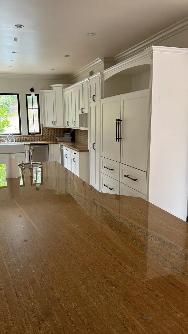 Modern white Calabasas kitchen with a brown granite island countertop.