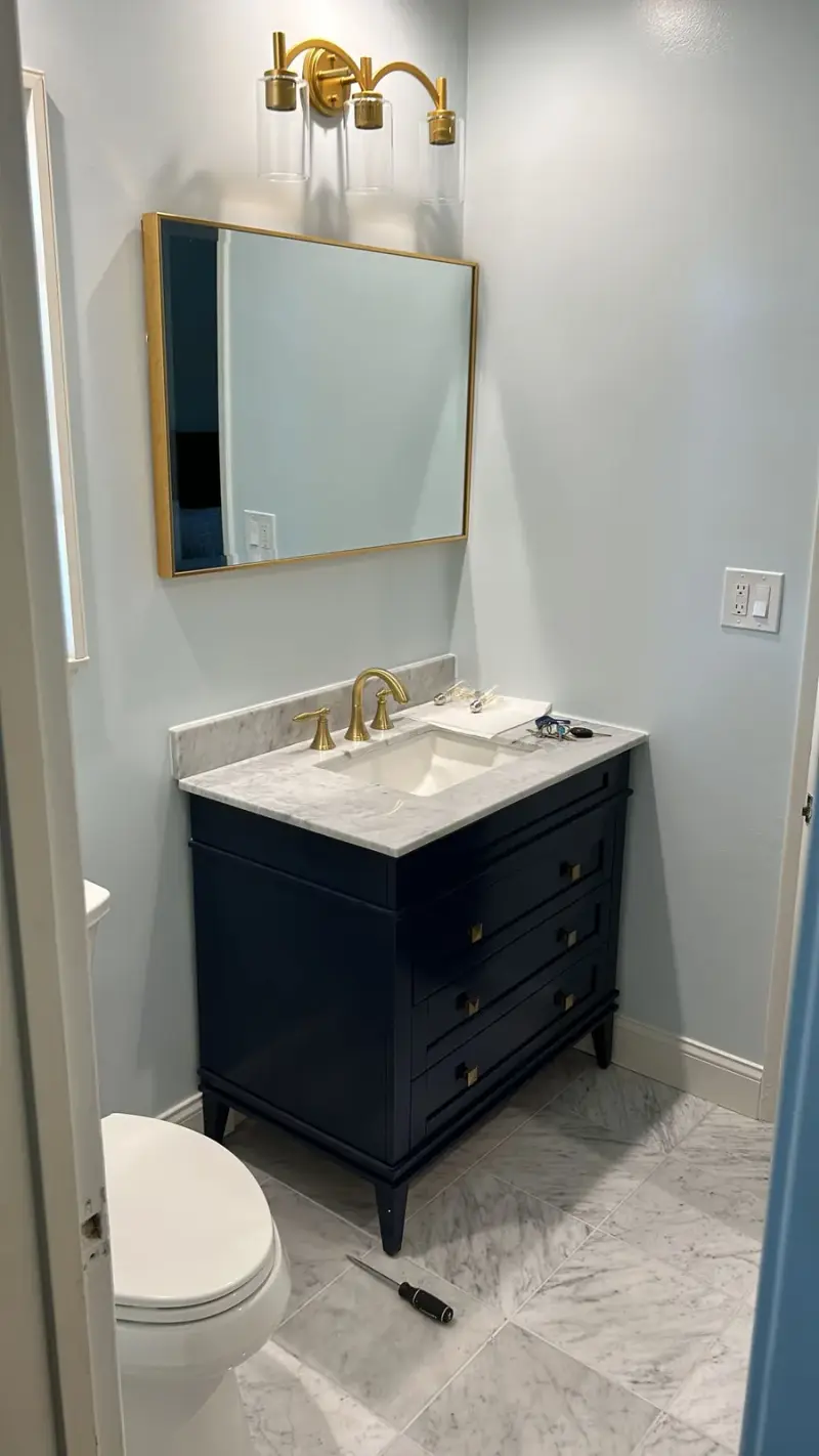 Navy blue bathroom vanity with gold fixtures and a marble countertop in Woodland Hills.