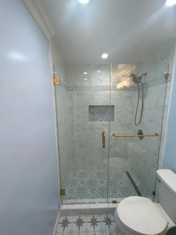 Walk-in shower with marble tile and gold fixtures in a Woodland Hills bathroom remodel.