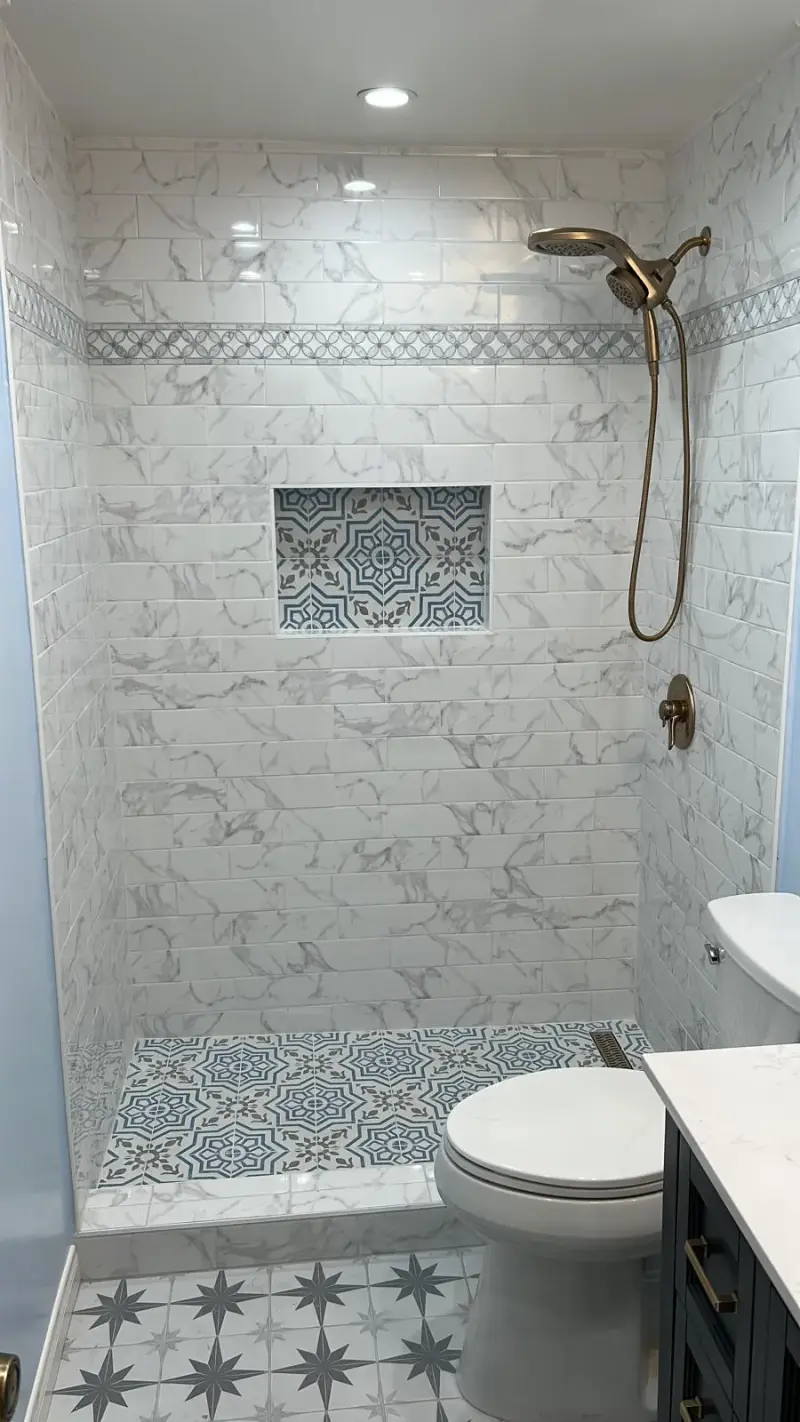 Marble shower with a patterned tile niche and bronze fixtures in a Woodland Hills bathroom.