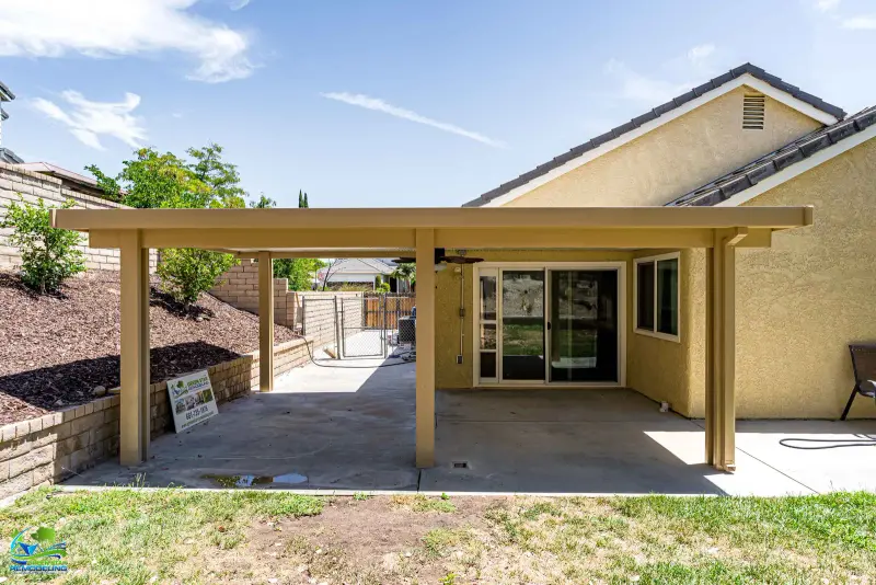 Tan aluminum patio cover extending over a Santa Clarita backyard patio.